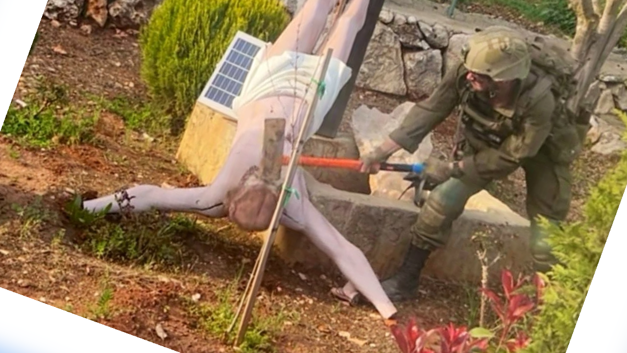 جندياً إسرائيلياً يستخدم مطرقة ثقيلة (sledgehammer) لتحطيم رأس تمثال يسوع المصلوب.